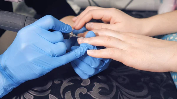 The manicurist makes manicure procedure of recovery and nail extensions on the nails of the girl in the nail salon — Stock Photo, Image