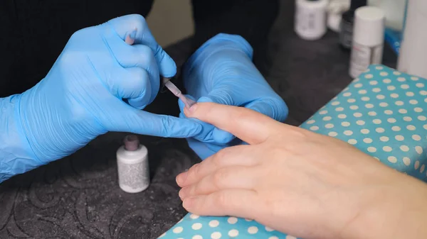 Closeup shot of a beautician applying nail polish to female nail in a nail salon — Stock Photo, Image
