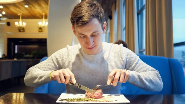Joven corte carne carne carne carne comer disfrutando de la cena en el restaurante —  Fotos de Stock