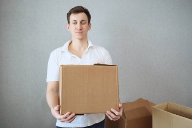 Holding ve yeni ev cardbox taşıyan genç teslimatçı