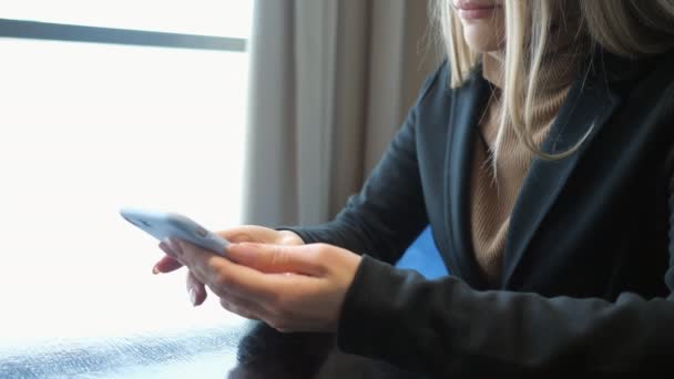 Onherkenbaar meisje met telefoon zitten aan een tafel in een café — Stockvideo