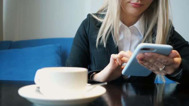 Unrecognizable business woman in suit with phone sitting at a table in a cafe, — Stock Video