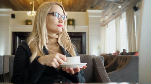 Sarışın kadın zevk kafede iyi duygu ile sıcak kahve içme — Stok video