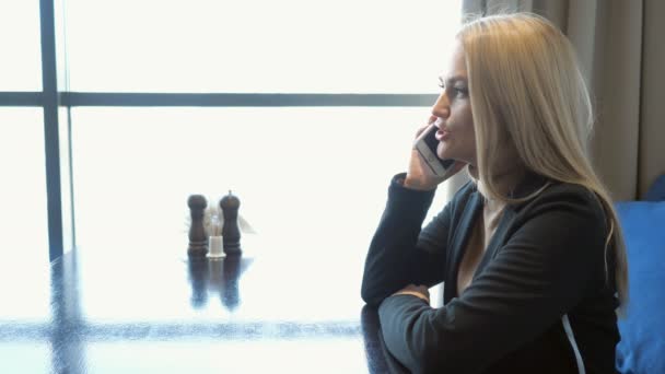 Jeune femme d'affaires en costume assis à la table dans un café, parlant sur un téléphone portable — Video