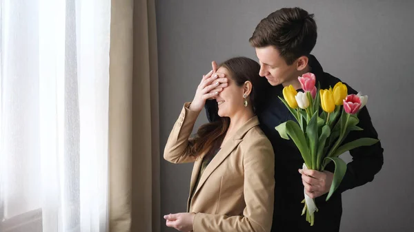 Mulher surpresa receber flores de tulipa de seu namorado — Fotografia de Stock