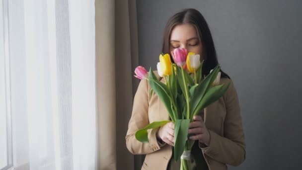 Mooi meisje met een boeket van tulpen thuis — Stockvideo