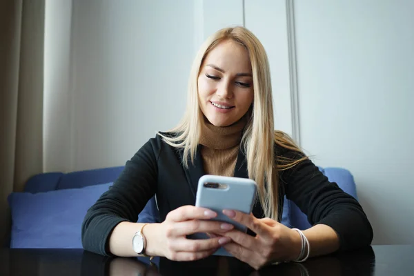 Gyönyörű fiatal nő ül egy asztalnál egy kávézóban telefon — Stock Fotó