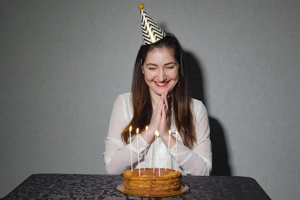 Mujer sola celebra una fiesta, él se sienta solo en una mesa con un pastel y una vela —  Fotos de Stock