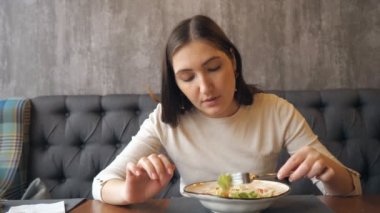 Genç kadın bir kafede, ağır çekim Sezar salata yemek