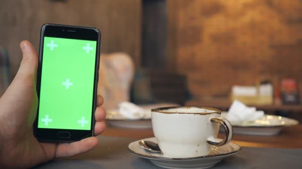 Manos humanas está sosteniendo Smartphone con pantalla verde en la cafetería — Vídeo de stock
