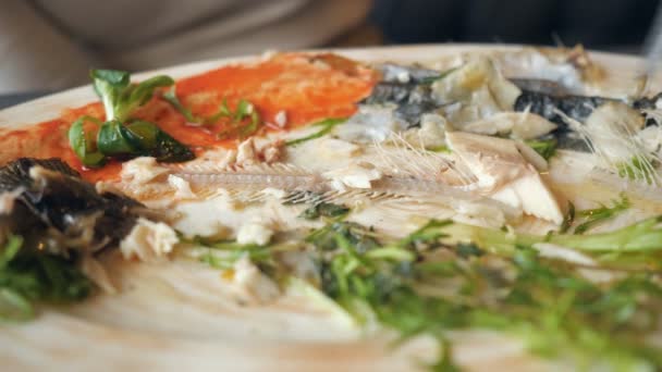 Женщина ест остатки рыбы с ножом и вилкой в кафе — стоковое видео