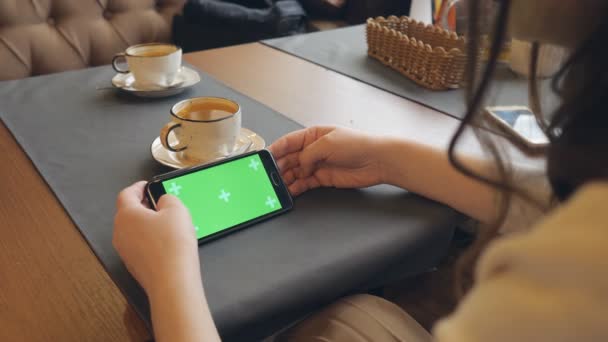 Swoman utilizando el teléfono celular móvil con pantalla táctil verde en la cafetería — Vídeo de stock