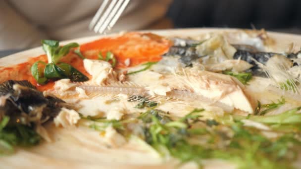 Mujer comiendo sobras de pescado con cuchillo y tenedor en la cafetería — Vídeos de Stock