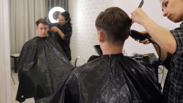 Un homme se fait couper les cheveux par un coiffeur. — Video