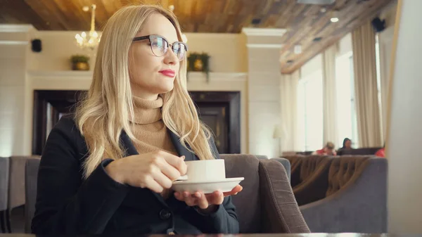 Kobieta blonde wypić gorącą kawę z uczucie dobry w kawiarni — Zdjęcie stockowe