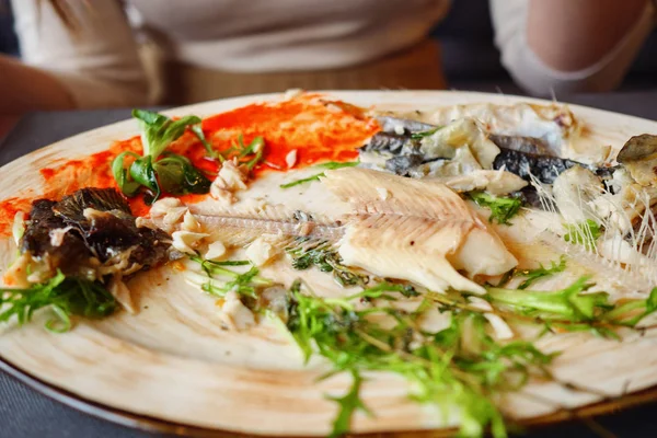 Mujer comiendo sobras de pescado con cuchillo y tenedor en la cafetería —  Fotos de Stock