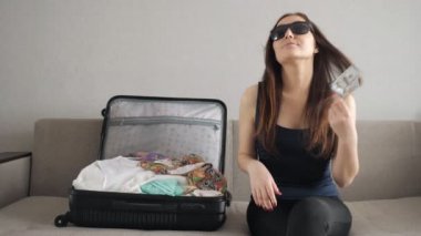 güneş gözlüğü mutlu kız kanepe, sallayarak ve atar dolar üzerinde oturur