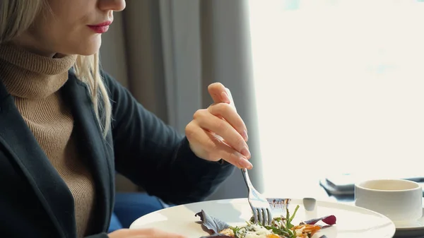 Mujer irreconocible comiendo ensalada sentada en la cafetería —  Fotos de Stock