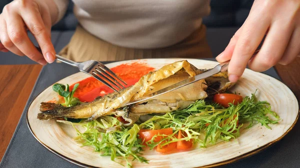 Close up de mulher comendo bife de peixe com faca e garfo — Fotografia de Stock