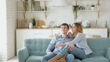Çift rahat mavi kanepe modern mutfakta TV izlerken oturur