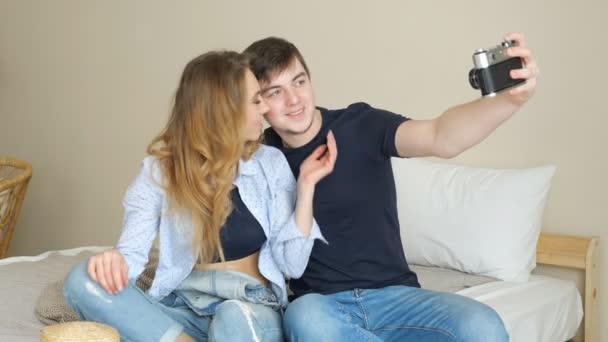 Meisje jongen zitten op bed maken selfie met oude camera poseren — Stockvideo