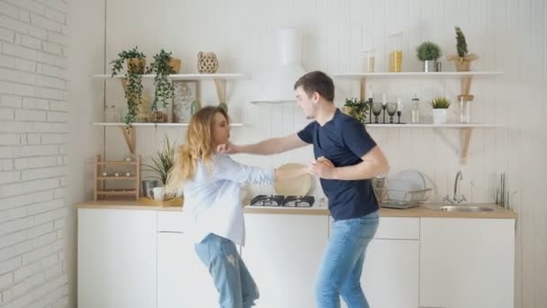 Joven pareja alegre divertirse bailando en la cocina en casa — Vídeos de Stock