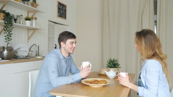 Blond dziewczyna i facet ma śniadanie picia herbaty w kuchni — Wideo stockowe