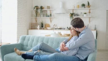 ağır çekim bir adam kanepede oturan ve mutfakta öpüşme Bayan hugs