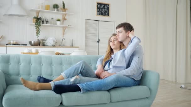 Homem abraços senhora sentado no sofá e beijando na cozinha — Vídeo de Stock