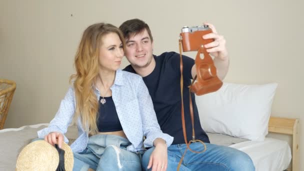 Κορίτσι άντρας κάθεται στο κρεβάτι κάνει selfie με παλιά κάμερας θέτοντας — Αρχείο Βίντεο