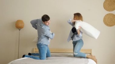 yatakta dizlerinin üzerinde ayakta yastıklar ile gülüyor çift kavgalar