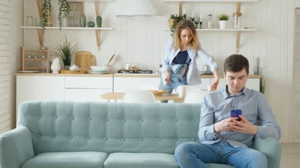 Vrouw wegneemt gerechten man zit op de Bank met telefoon — Stockvideo