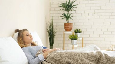 güzel sarışın kız ışık yatak odasında yatak, Saksı bitkiler ile yalan