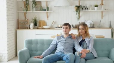 Çift rahat mavi kanepe modern mutfakta TV izlerken oturur