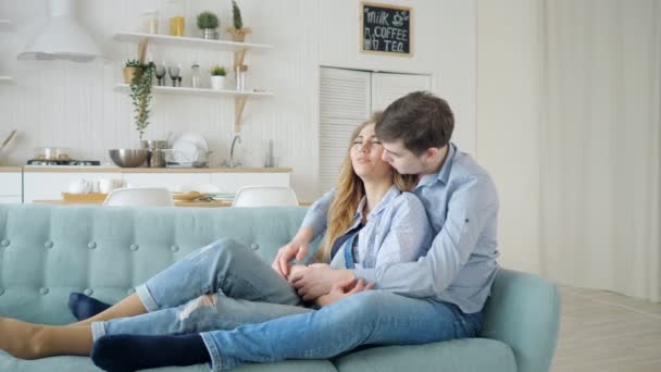 Uomo abbracci signora seduta sul divano e baci in cucina — Video Stock