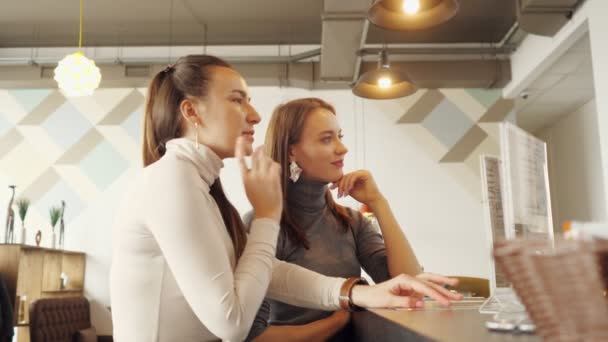 Deux femmes discutent du menu et choisissent de la nourriture dans un café debout au comptoir du bar . — Video