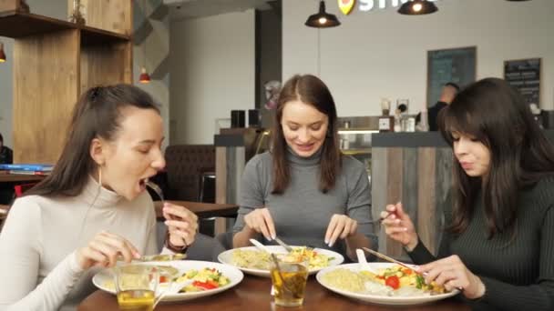 Три друзі-жінки їдять разом у кафе і розмовляють, насолоджуючись їжею . — стокове відео