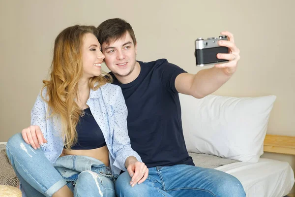 stock image girl guy sit on bed make selfie with old camera posing