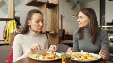İki kadın arkadaş birlikte yemek kafe ve konuşmak, onların yiyecek zevk içinde.