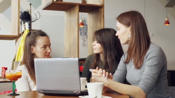 Colleagues women discuss joint project in cafe in the coworking center using a laptop. — Stock Video