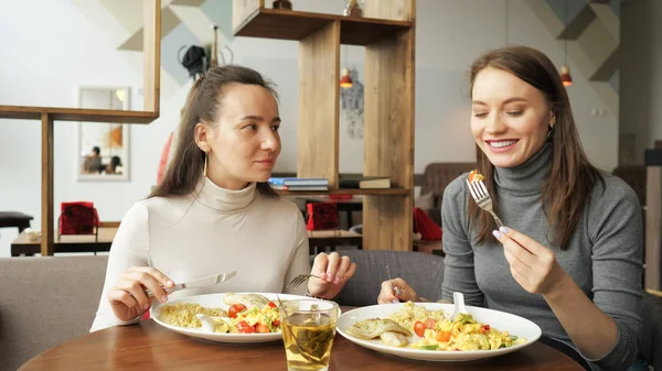 Zwei Freundinnen essen zusammen im Café und unterhalten sich, genießen ihr Essen. — Stockfoto