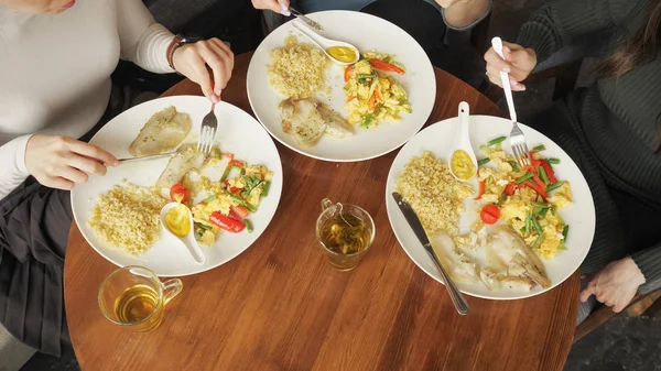 Tres amigas están comiendo en la cafetería. Platos en la mesa vista superior . — Foto de Stock