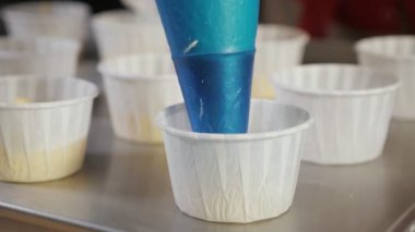 Pasta çantası ile şefler eller kağıt bardakları kek pişirme için hamur doldurun.