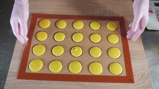 Baker is cooking macaroons on stencil silicone mat on the table, preparing for baking pasta. — Stock Video