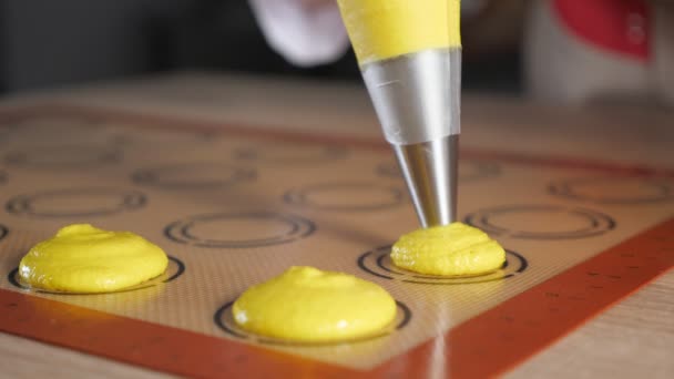 Кондитер готовит макароны. Наливание теста на трафаретный силиконовый коврик . — стоковое видео