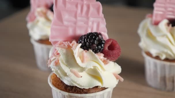 Cupcakes con crema, gofres y bayas frescas en vasos de papel sobre la mesa . — Vídeos de Stock