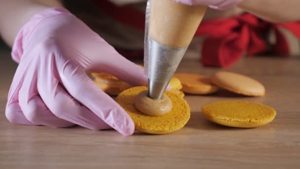 Pastelero está llenando macarrones de limón con crema usando bolsa de confitería . — Vídeos de Stock