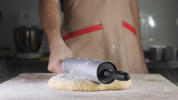 Baker chef roule la pâte avec rouleau à pâtisserie sur la table . — Video