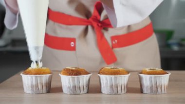 Pasta şefi pasta çantası ile kağıt bardakları beyaz krem cupcakes dekorlar.