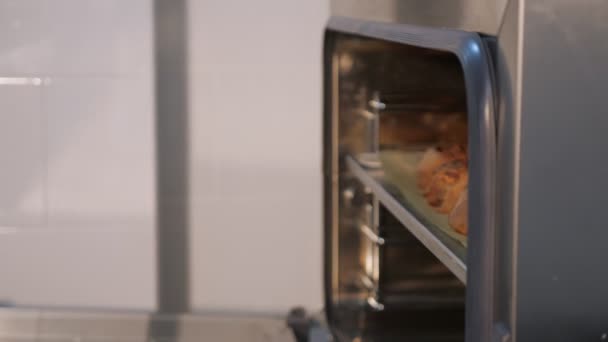 Chef pâtissier sort de la plaque de cuisson du four avec des rouleaux de cannelle .